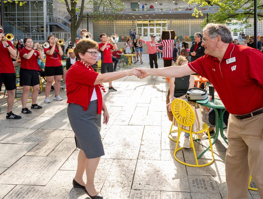 Outdoors at the Memorial Union Terrace, Chancellor Emerita Blank reaches out to take the hand of her husband, Hanns Kutter, as they dance to music played by the UW marching band.