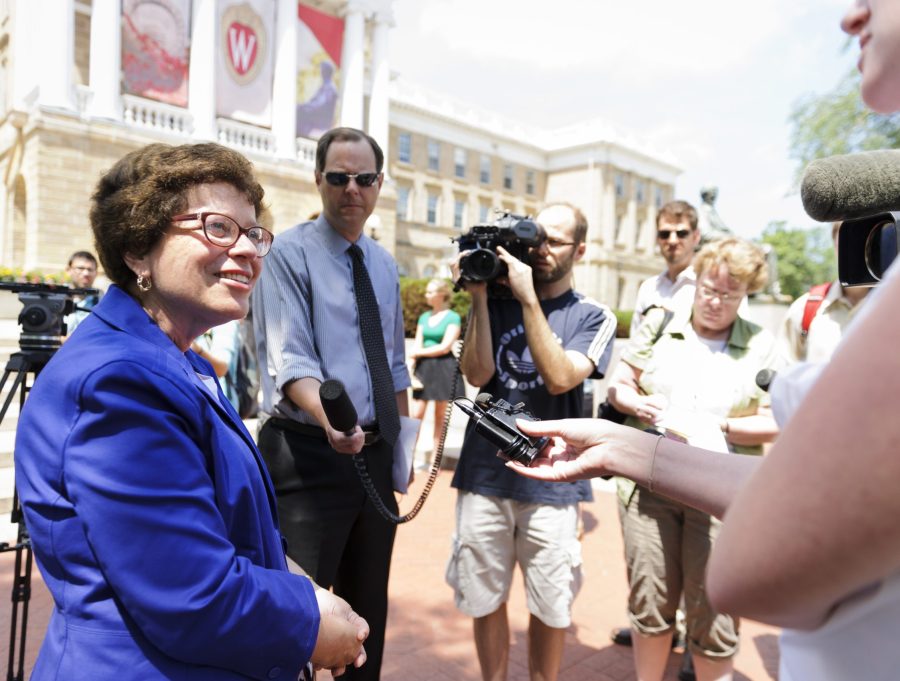 Chancellor Blank talks with news media outside Bascom Hall on a bright sunny day. She smiles as she speaks to a reporter.