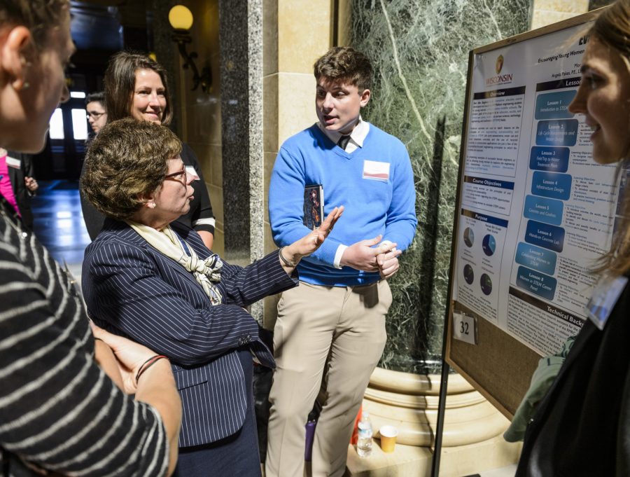 Chancellor Blank asks questions of student teammates, left to right, Renee Olley, Tyler Klink and Morgan Sanger, about their research project on display in the Wisconsin State Capitol.