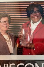 Rebecca Blank stands next to Valarie King-Bailey who is holding a glass award vase honoring her with a UW Entrepreneurial Achievement Award.